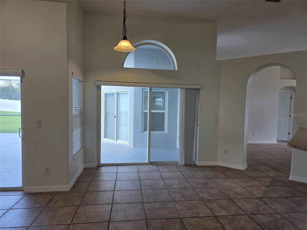 A tiled dining area features a vaulted ceiling, a pendant light, and sliding glass doors — 881 SENECA TRAIL, ST CLOUD, FL