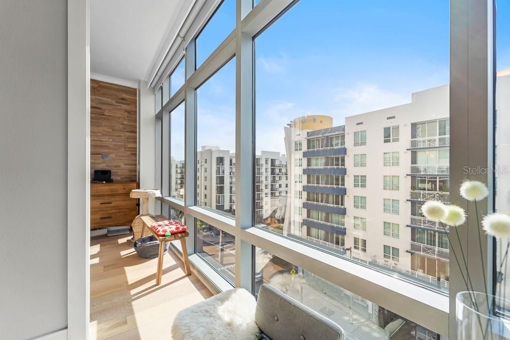 A sunlit room with floor-to-ceiling windows, wood-paneled walls, and a view of urban buildings — 1120 E KENNEDY BOULEVARD UNIT 612, TAMPA, FL