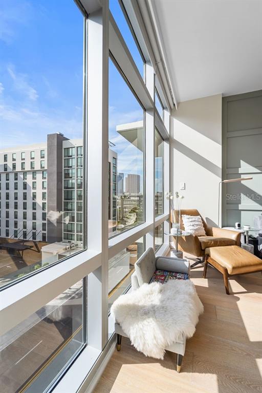 A sunlit room features floor-to-ceiling windows, a leather armchair with ottoman, and a small bench — 1120 E KENNEDY BOULEVARD UNIT 612, TAMPA, FL