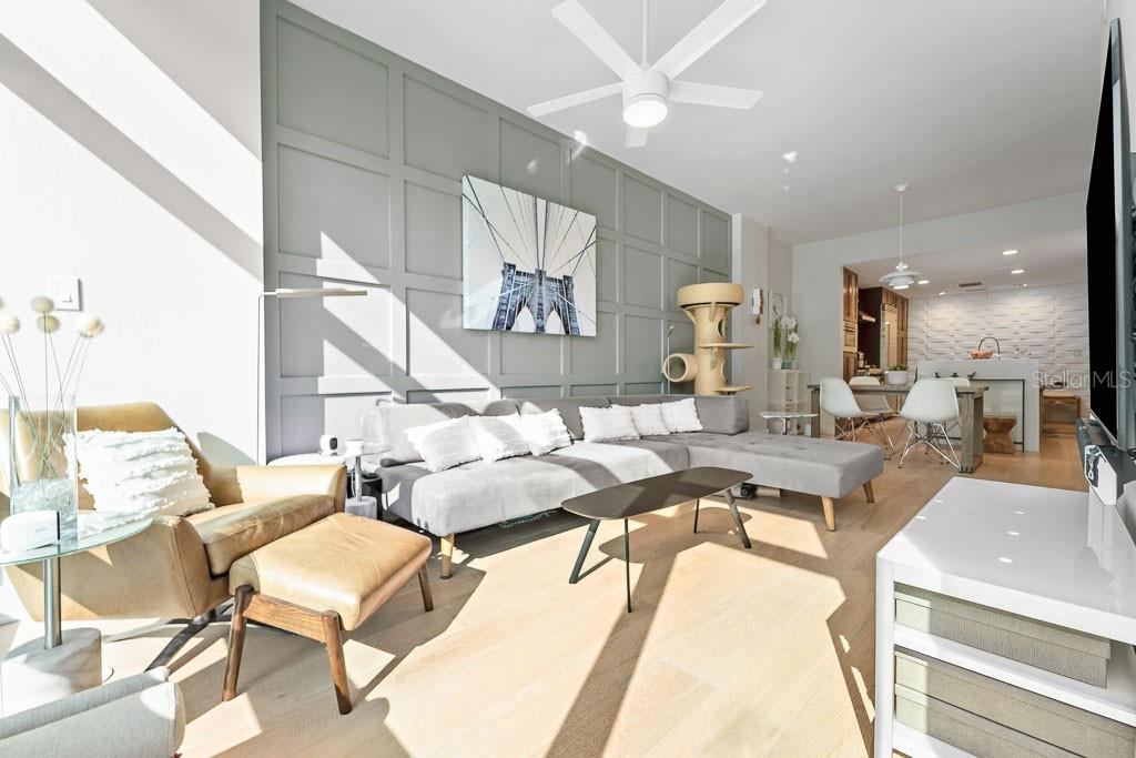A living room features a gray paneled wall, a sectional sofa, and a leather armchair — 1120 E KENNEDY BOULEVARD UNIT 612, TAMPA, FL