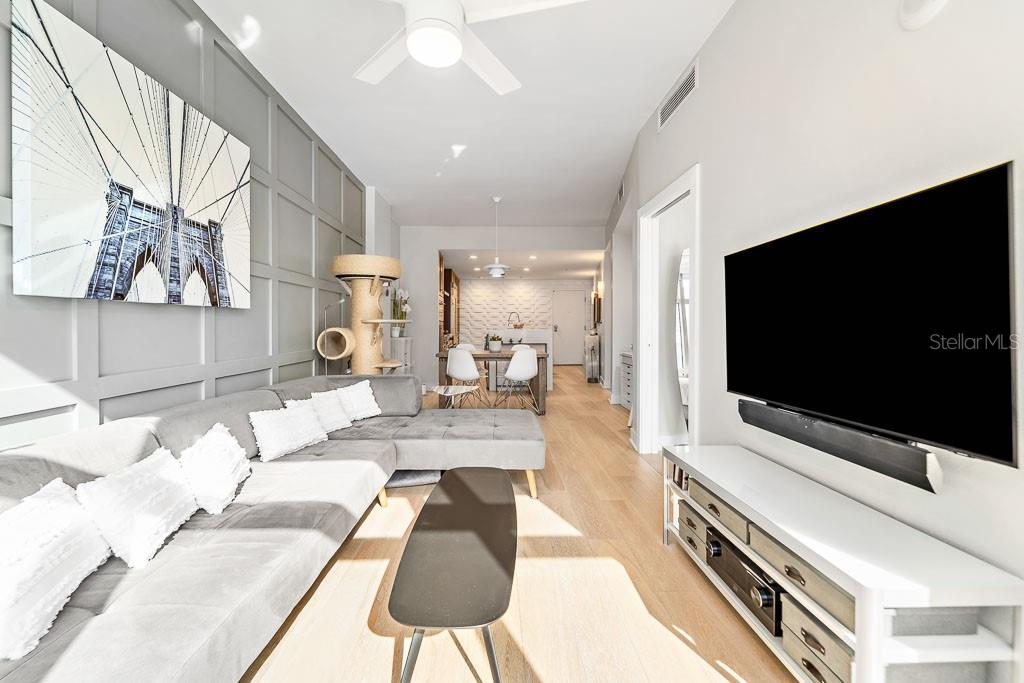 A modern living room features a gray sectional sofa, a wall-mounted television, and light wood flooring — 1120 E KENNEDY BOULEVARD UNIT 612, TAMPA, FL