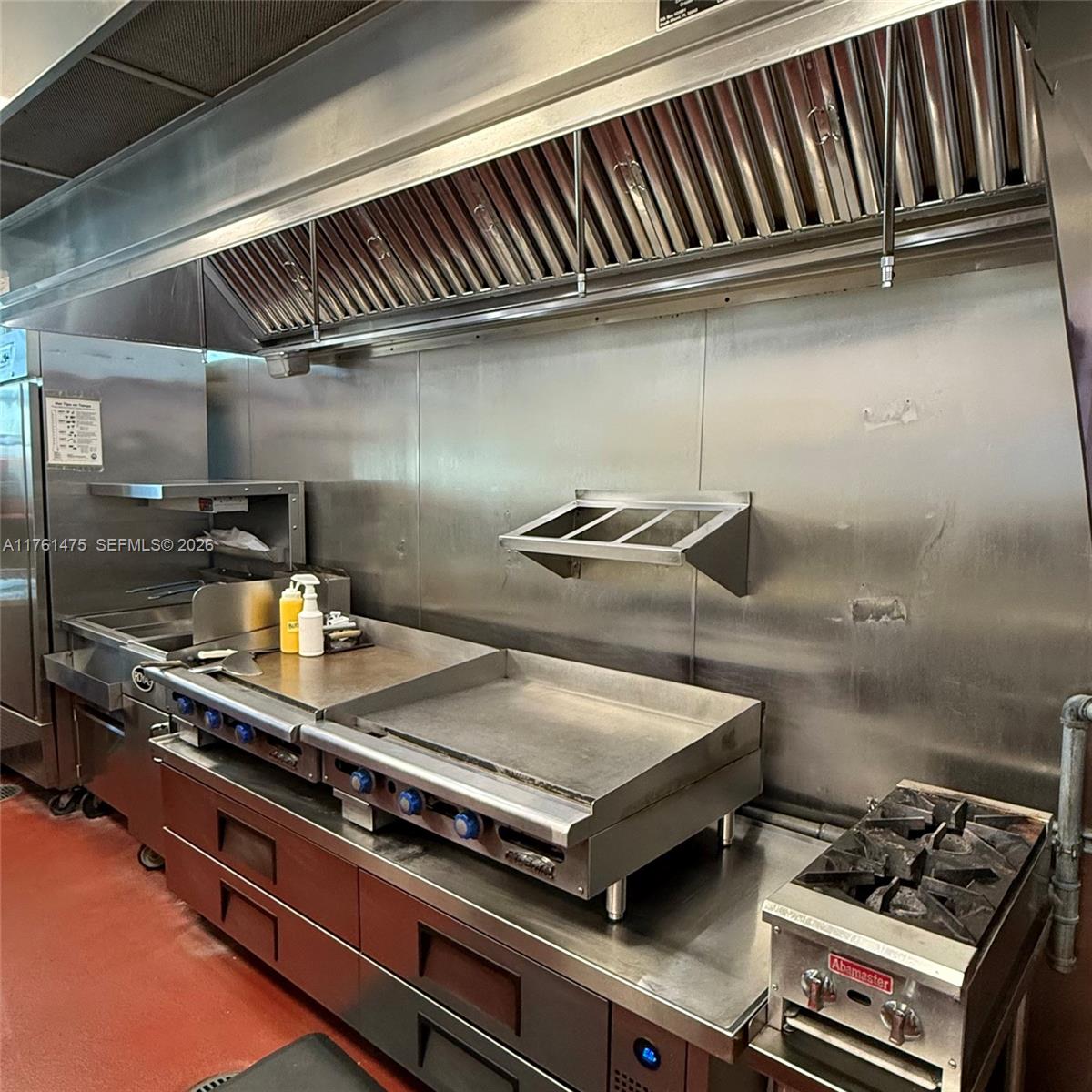 A commercial kitchen features stainless steel appliances, a ventilation hood, and a red floor — 58 ST, Doral FL 33178, DORAL, FL