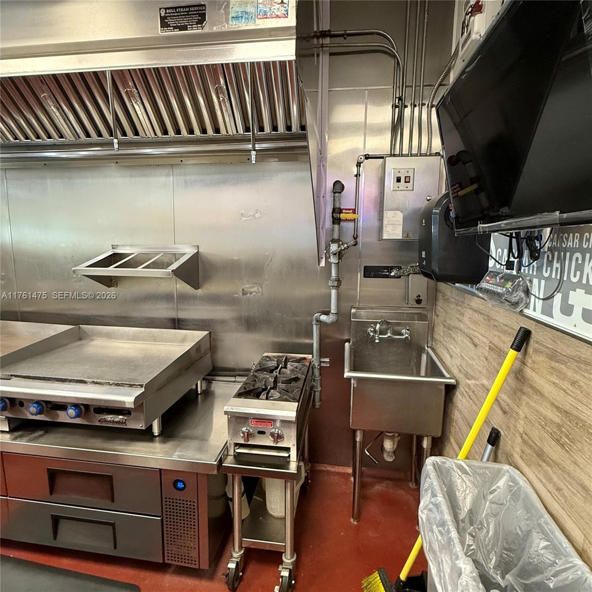 A commercial kitchen features stainless steel appliances, a sink, and a vent hood — 58 ST, Doral FL 33178, DORAL, FL