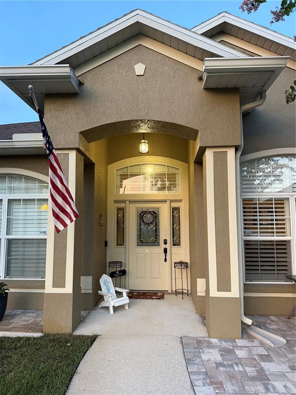 The exterior of a house features a covered entryway, a front door, and an American flag — 12734 COLONNADE CIRCLE, CLERMONT, FL