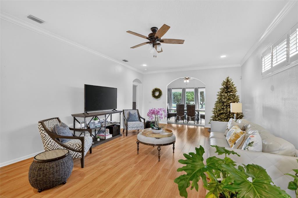 A living room features light wood flooring, a ceiling fan, and an arched entryway — 5304 TREASURE VIEW WAY, LEESBURG, FL