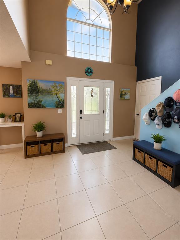 A bright entryway features tiled floors, a white front door, and two storage benches — 2254 MARBLE AVENUE, SPRING HILL, FL