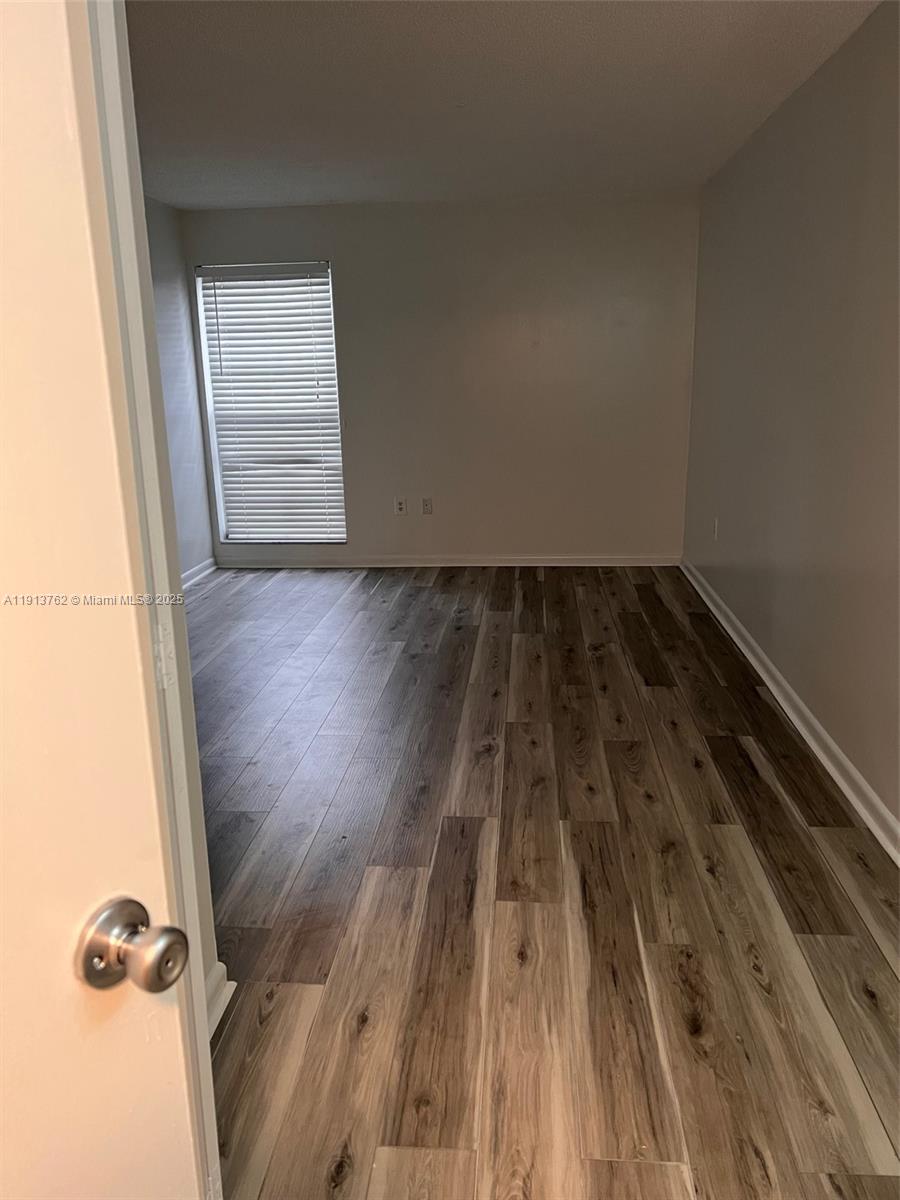 An empty room features light-colored walls, wood-look flooring, and a window with white blinds — 12035 NE 2nd Ave # A111, North Miami FL 33161, NORTH MIAMI, FL