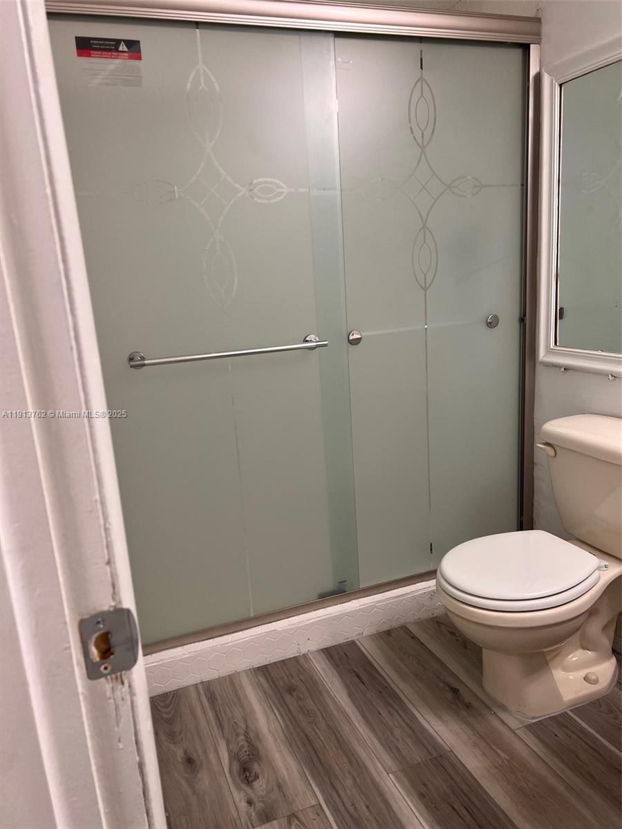 A bathroom features a frosted glass shower door, a toilet, and wood-look flooring — 12035 NE 2nd Ave # A111, North Miami FL 33161, NORTH MIAMI, FL