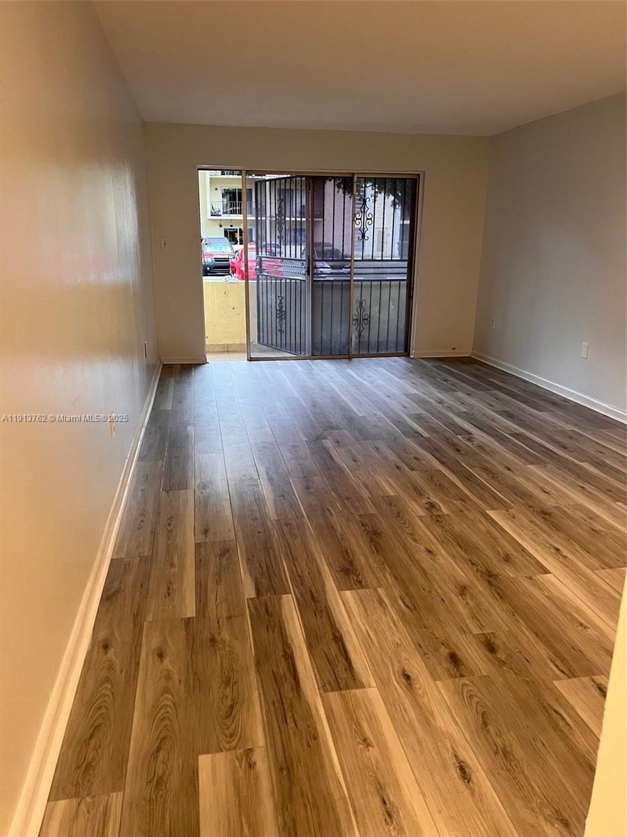 This room features light-colored walls, wood-look flooring, and a sliding glass door with security bars — 12035 NE 2nd Ave # A111, North Miami FL 33161, NORTH MIAMI, FL