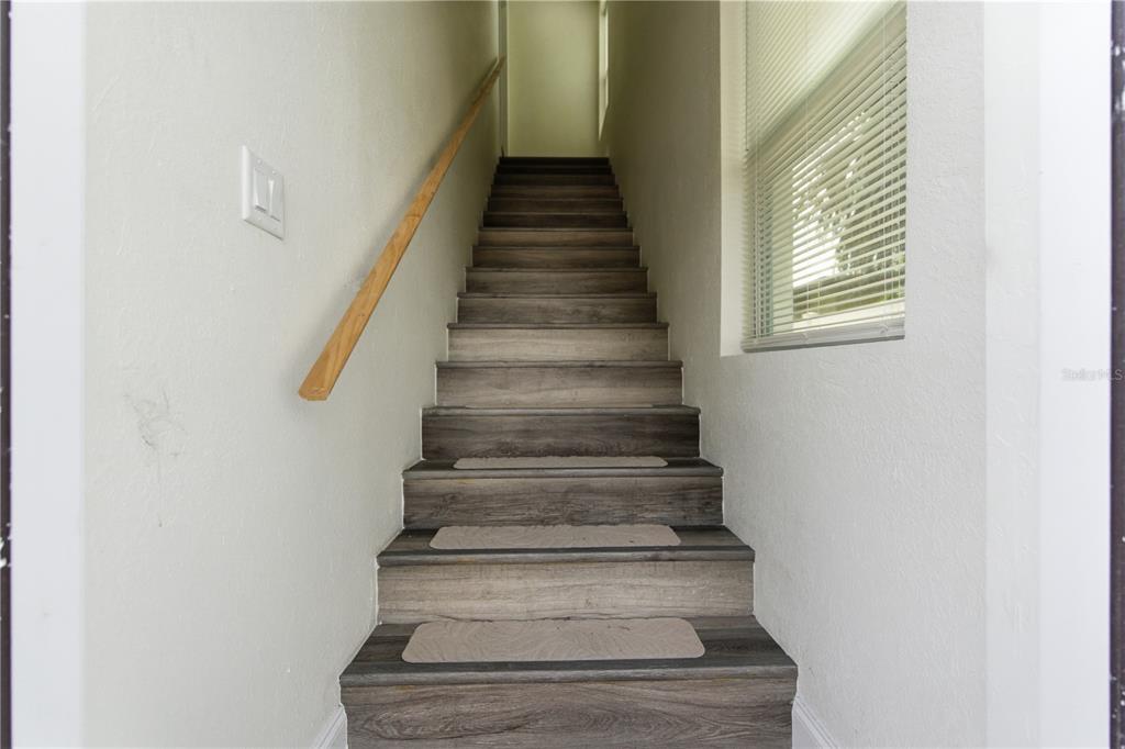 A staircase with wood-look treads and beige carpet runners leads to an upper landing — 1901 31ST STREET S UNIT 1/2, ST PETERSBURG, FL