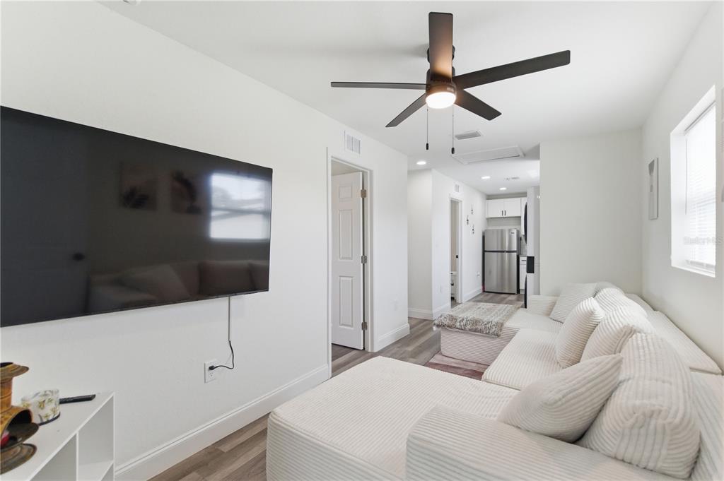 A living room features a wall-mounted television, a white sectional sofa, and a ceiling fan — 1901 31ST STREET S UNIT 1/2, ST PETERSBURG, FL