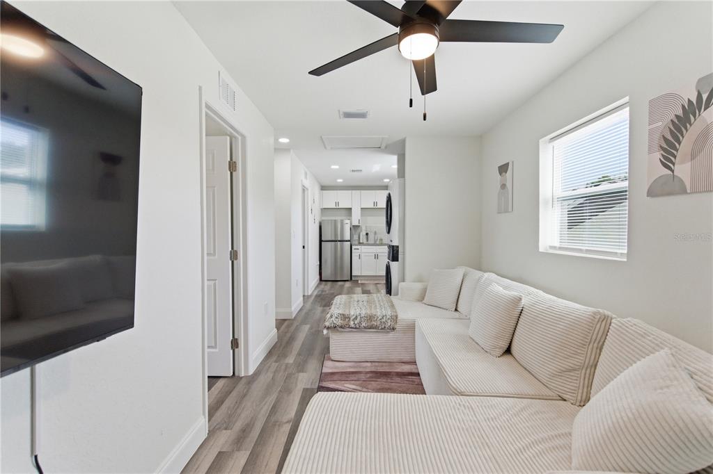 A living room with a sectional sofa, ceiling fan, and a view into the kitchen — 1901 31ST STREET S UNIT 1/2, ST PETERSBURG, FL