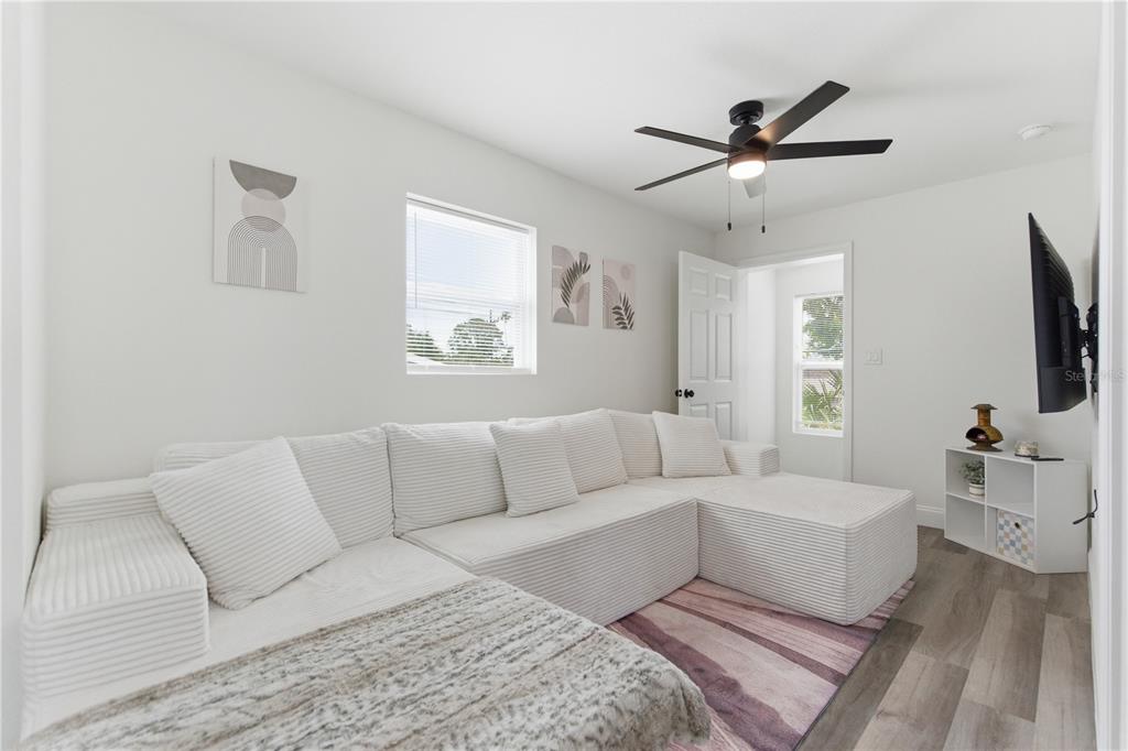A living room features a white sectional sofa, a ceiling fan, and a wall-mounted television — 1901 31ST STREET S UNIT 1/2, ST PETERSBURG, FL