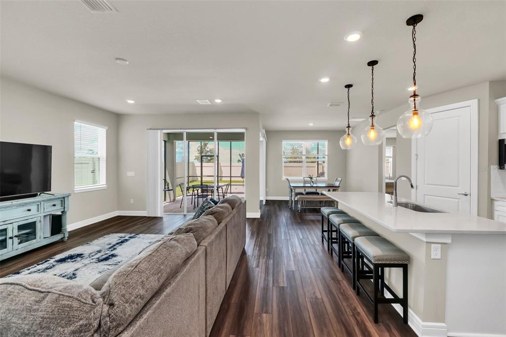 An open-concept living room and kitchen featuring dark wood floors, a breakfast bar, and patio — 2001 SPRING SHOWER CIRCLE, KISSIMMEE, FL