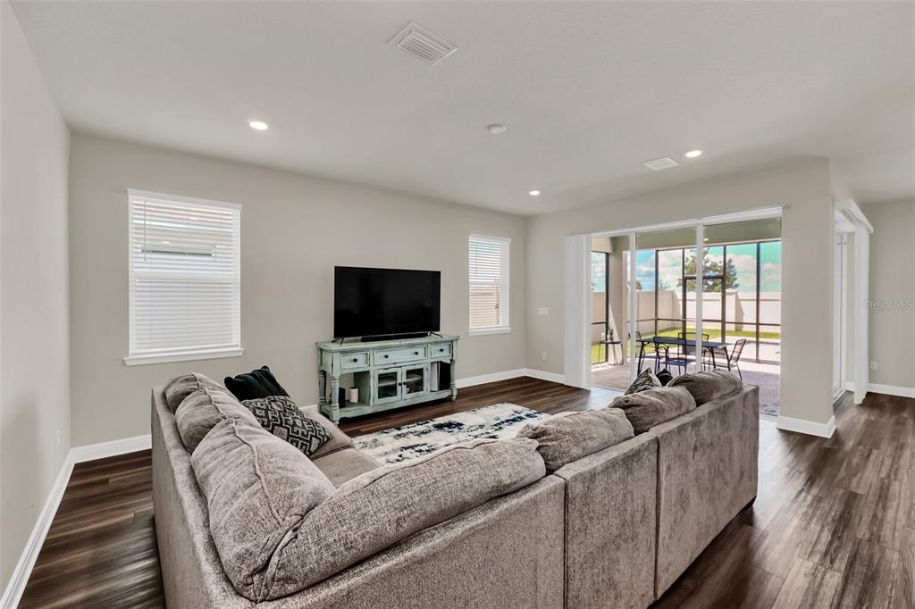A living room features a large sectional sofa, a television on a console, and sliding doors — 2001 SPRING SHOWER CIRCLE, KISSIMMEE, FL