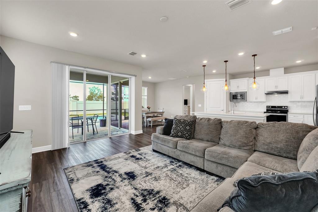 A living room with a gray sectional sofa, area rug, and open kitchen with white cabinets — 2001 SPRING SHOWER CIRCLE, KISSIMMEE, FL