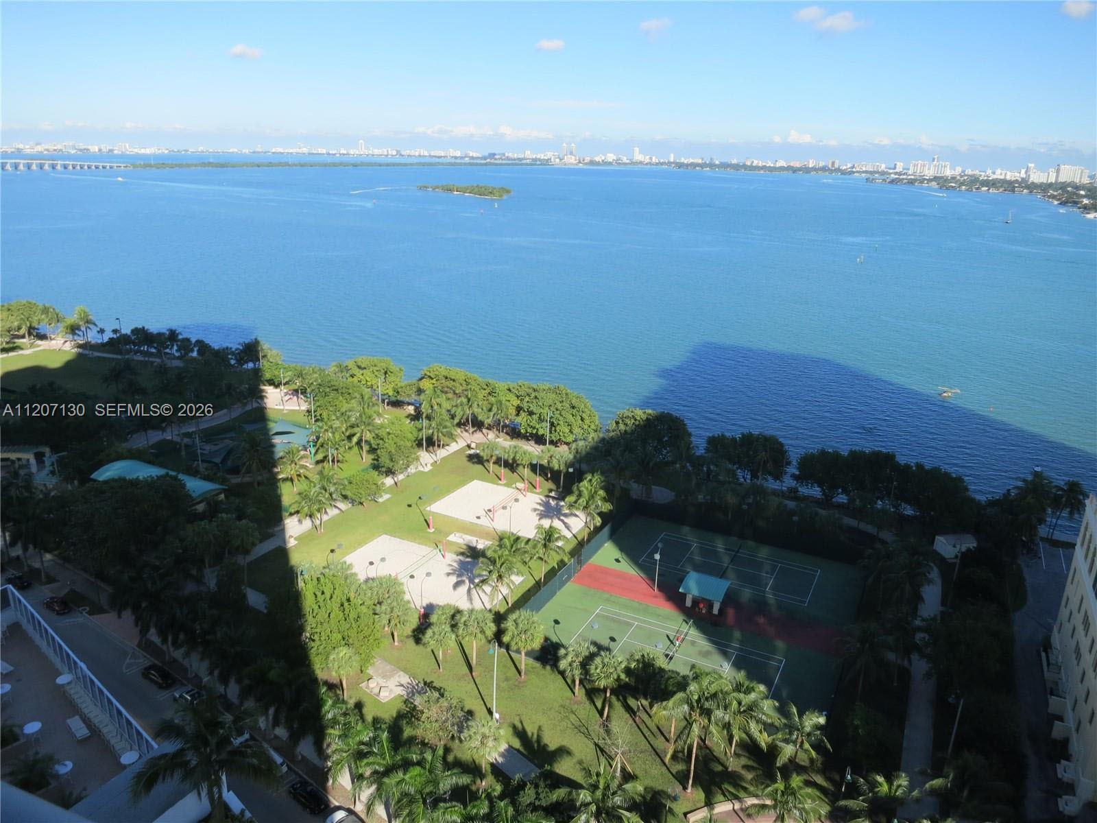 A modern living room features a grey velvet sofa, glass coffee table, and floor-to-ceiling windows — 1750 N Bayshore Dr # 3914, Miami FL 33132, MIAMI, FL