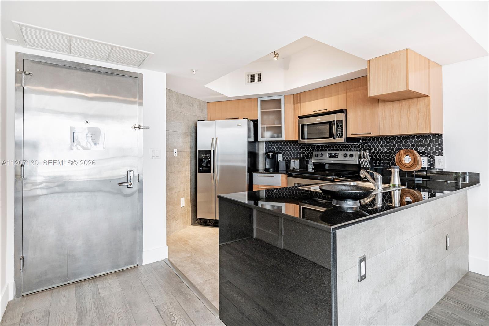 A modern kitchen features stainless steel appliances, black granite countertops, and light wood cabinetry — 1750 N Bayshore Dr # 3914, Miami FL 33132, MIAMI, FL