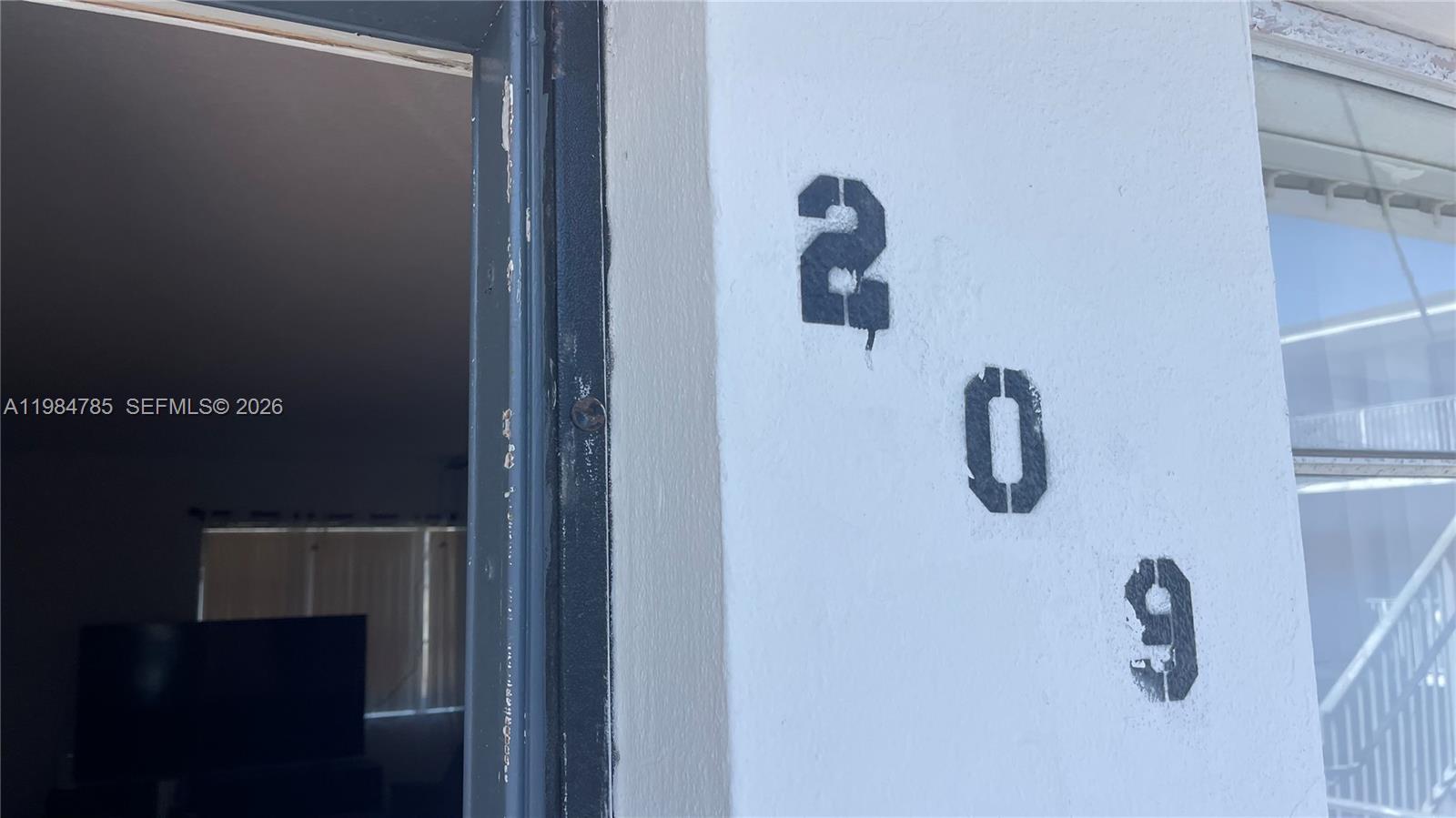 The number 209 is stenciled on a white exterior wall next to a doorway — 13700 NE 6th Ave # 209, North Miami FL 33161, NORTH MIAMI, FL