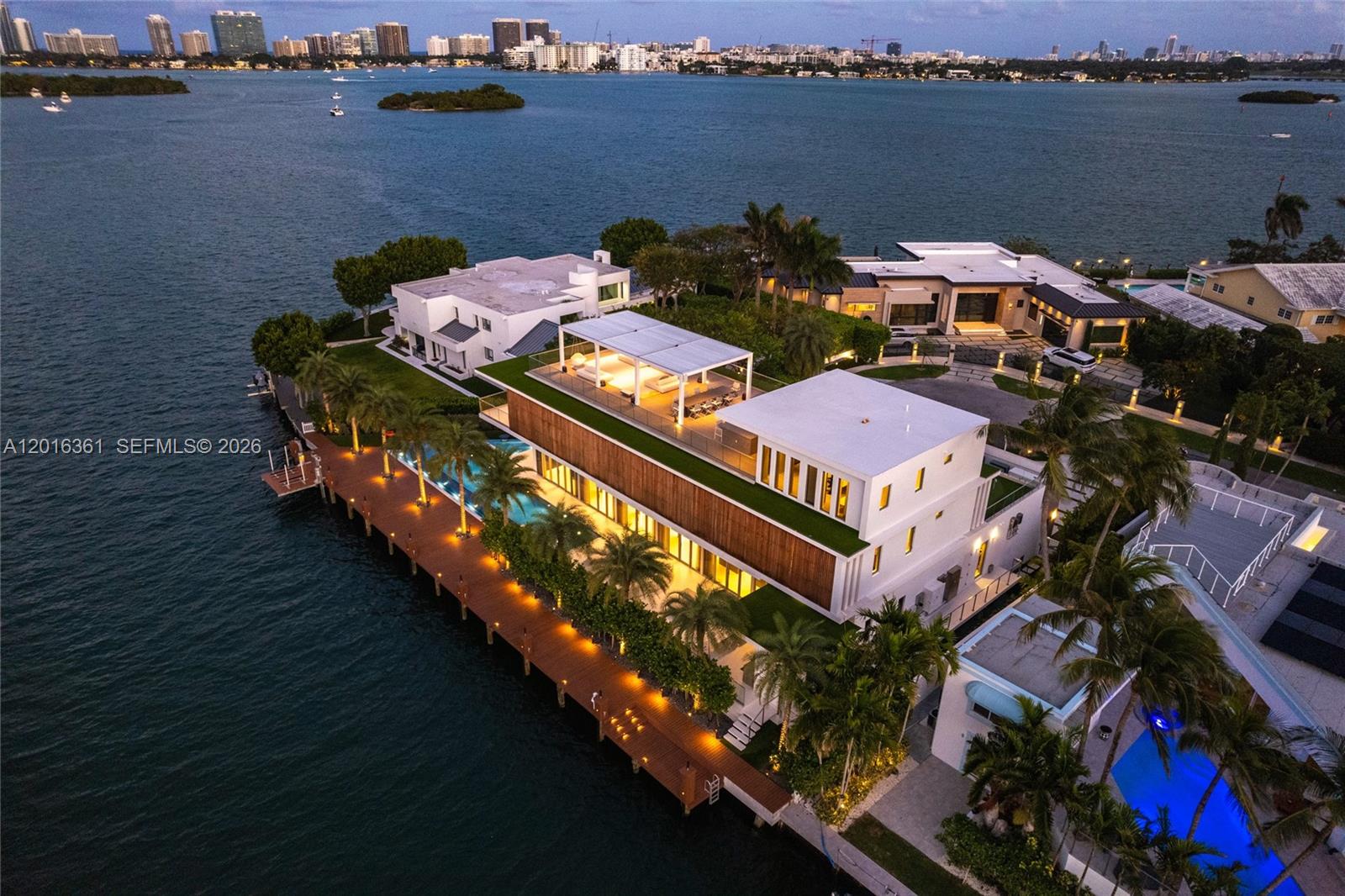 An aerial view shows a modern waterfront mansion with a large deck and swimming pool — 13390 Biscayne Bay Dr, North Miami FL 33181, NORTH MIAMI, FL