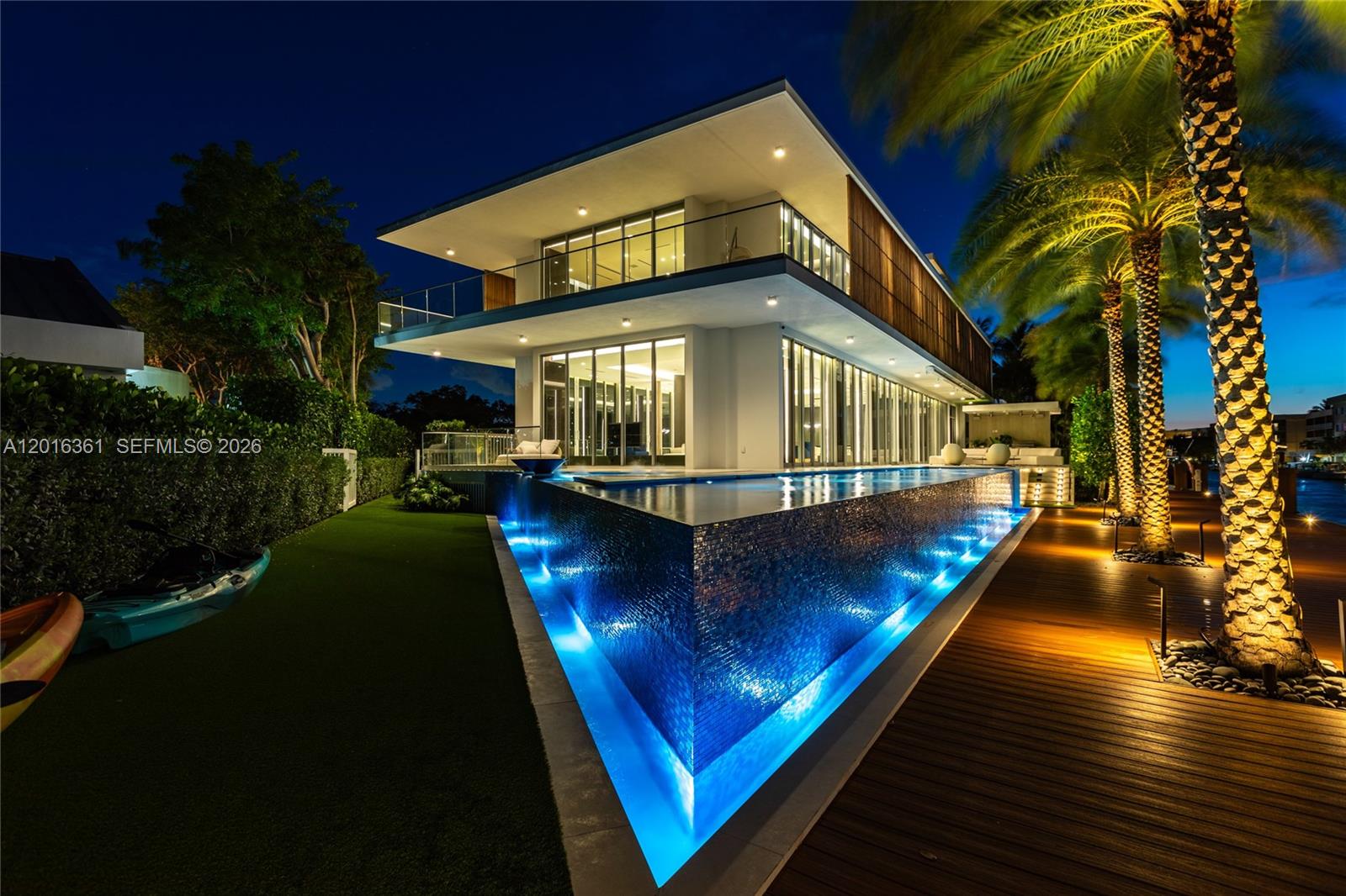 A modern two-story house at night features a glowing infinity pool and palm trees — 13390 Biscayne Bay Dr, North Miami FL 33181, NORTH MIAMI, FL