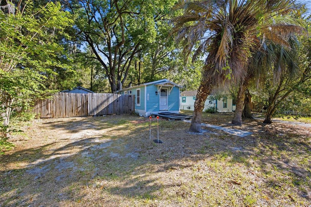 A small blue house sits on a dirt lot with palm trees and a wooden fence — 1032 NW 40TH AVENUE, GAINESVILLE, FL