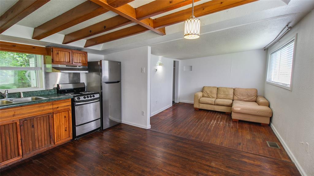A kitchen with wood cabinets and stainless steel appliances opens into a living area — 1709 CLOVERLAWN AVENUE, ORLANDO, FL