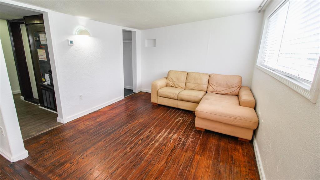 A living room with hardwood floors, white walls, and a tan sectional sofa — 1709 CLOVERLAWN AVENUE, ORLANDO, FL