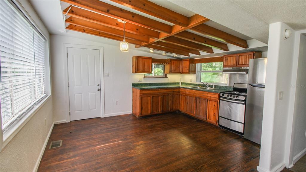 A kitchen with wood-beamed ceilings, dark wood cabinets, green countertops, and stainless steel appliances — 1709 CLOVERLAWN AVENUE, ORLANDO, FL