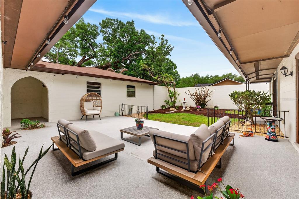 A covered patio with outdoor furniture overlooks a small backyard with a lawn and trees — 517 SAN SEBASTIAN PRADO, ALTAMONTE SPRINGS, FL