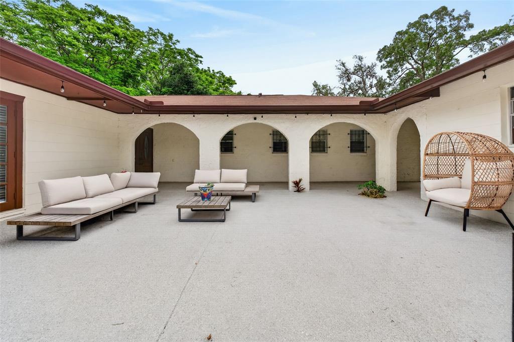 A spacious outdoor courtyard features a concrete patio, arched covered walkways, and modern patio furniture — 517 SAN SEBASTIAN PRADO, ALTAMONTE SPRINGS, FL