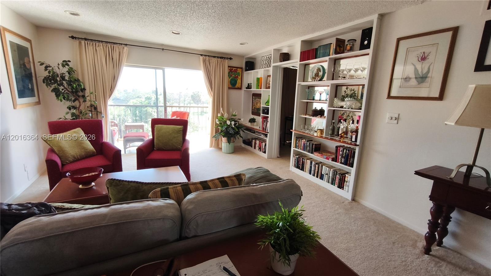 A living room features a gray sofa, two red armchairs, and built-in white shelving — 6100 S Falls Cir Dr # 404, Lauderhill FL 33319, LAUDERHILL, FL