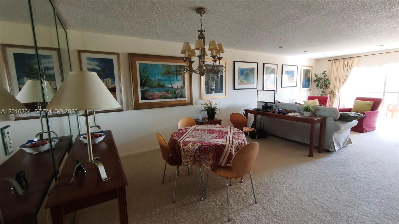 A dining area with a round table and chandelier sits adjacent to a living room — 6100 S Falls Cir Dr # 404, Lauderhill FL 33319, LAUDERHILL, FL