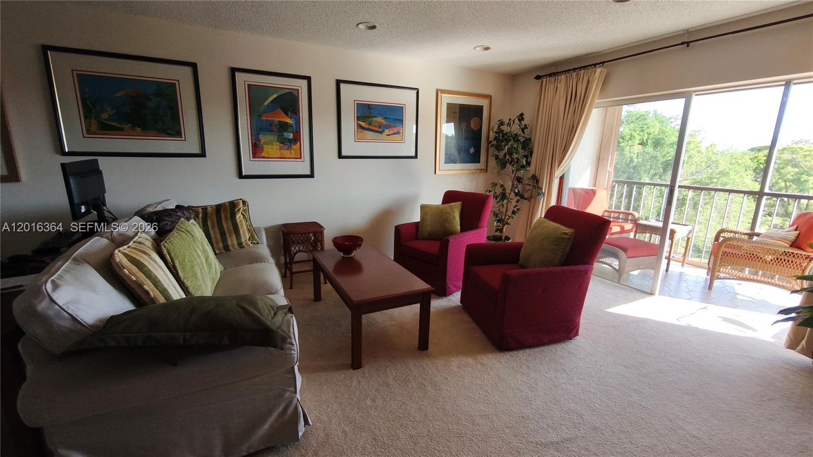 A living room features a sofa, two red armchairs, framed artwork, and a balcony view — 6100 S Falls Cir Dr # 404, Lauderhill FL 33319, LAUDERHILL, FL