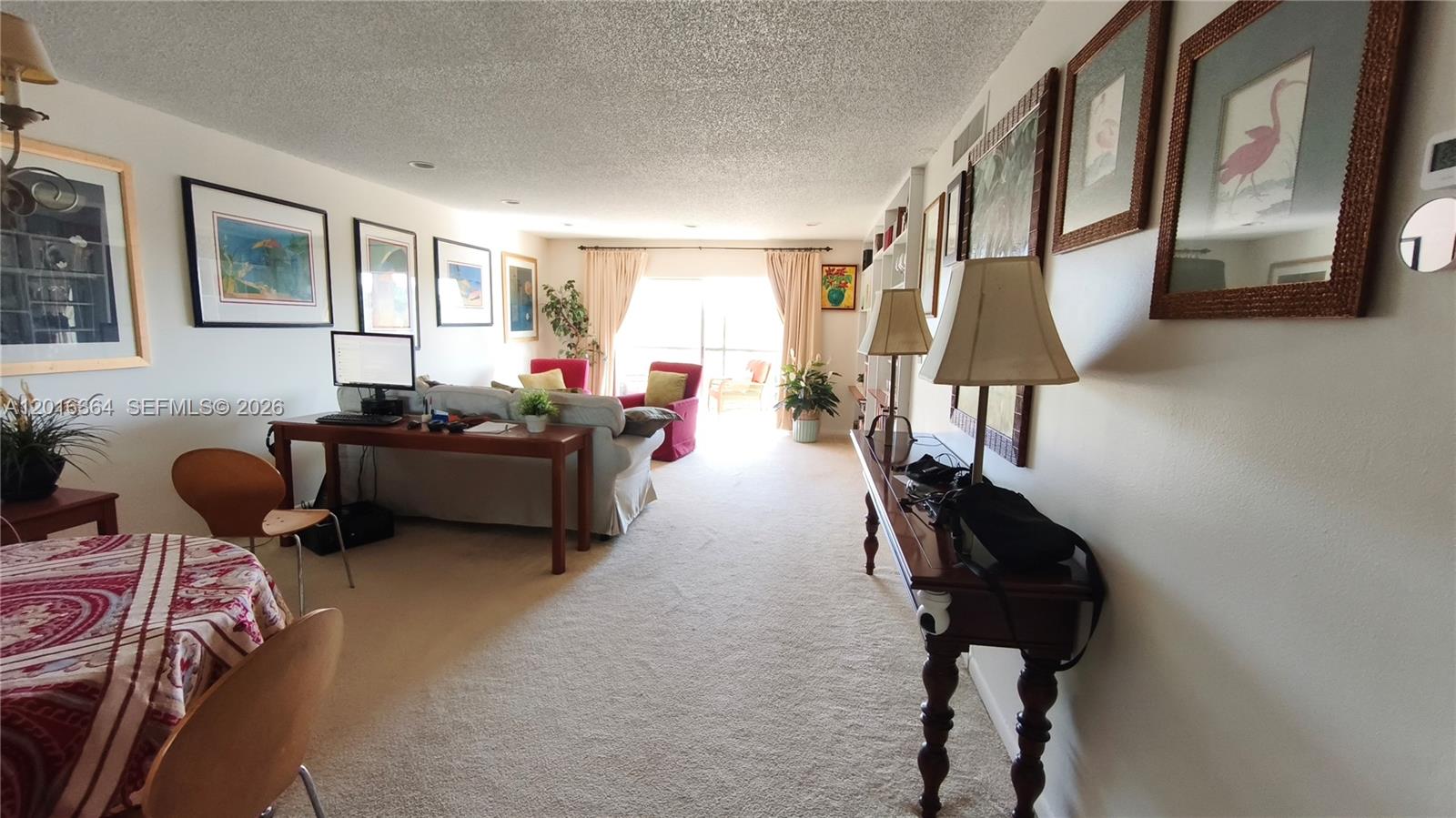 A living and dining area features carpeted floors, a desk, and framed wall art — 6100 S Falls Cir Dr # 404, Lauderhill FL 33319, LAUDERHILL, FL