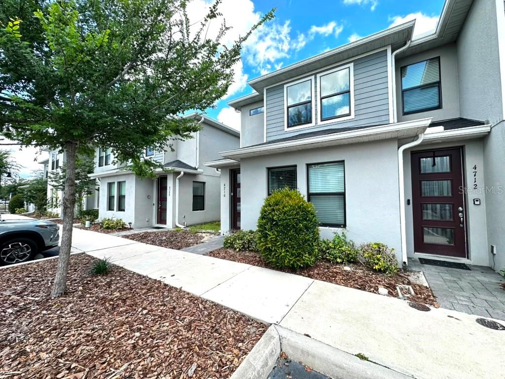 A two-story townhouse with a gray exterior, dark red front door, and a sidewalk — 4710 TERRA ESMERALDA DRIVE, KISSIMMEE, FL