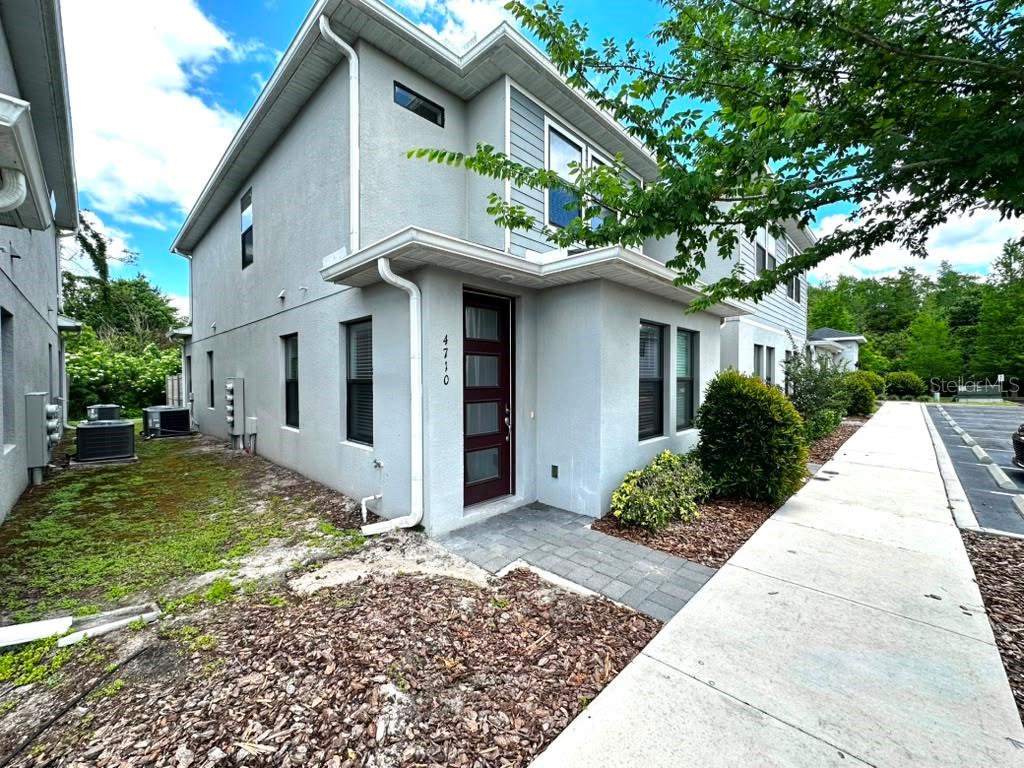 A two-story gray house with a dark red front door and a paved walkway — 4710 TERRA ESMERALDA DRIVE, KISSIMMEE, FL