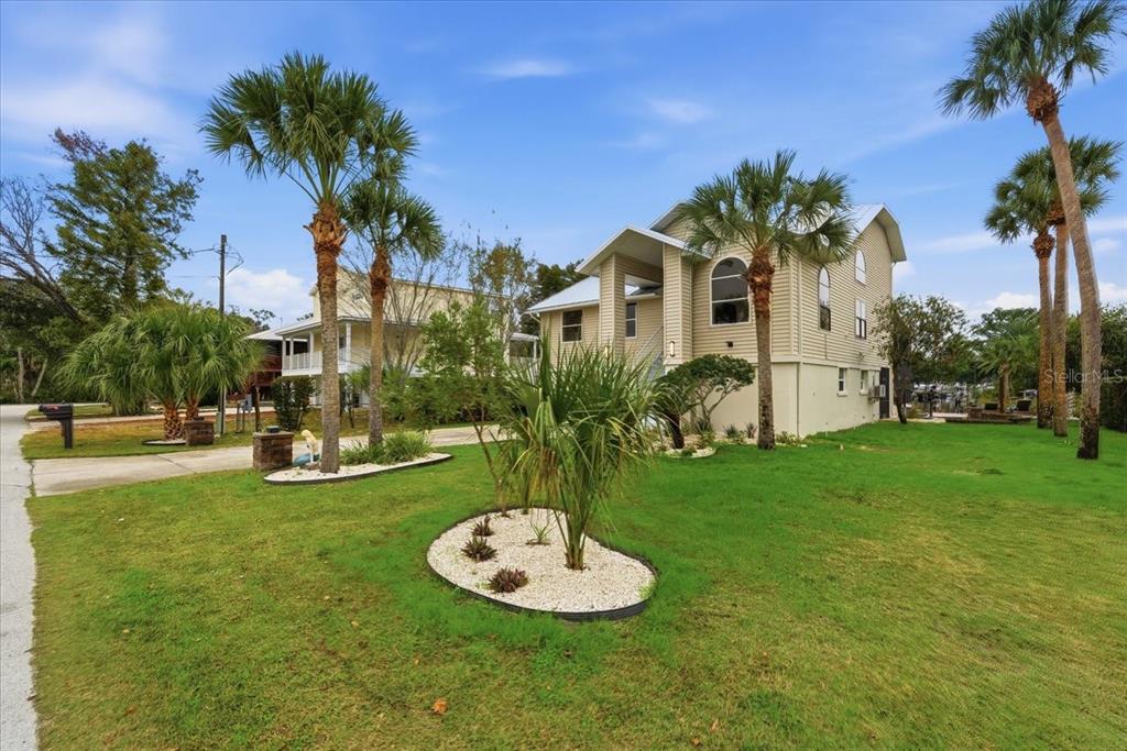A two-story house with light siding stands on a grassy lot with palm trees — 1821 NW 20TH AVENUE, CRYSTAL RIVER, FL