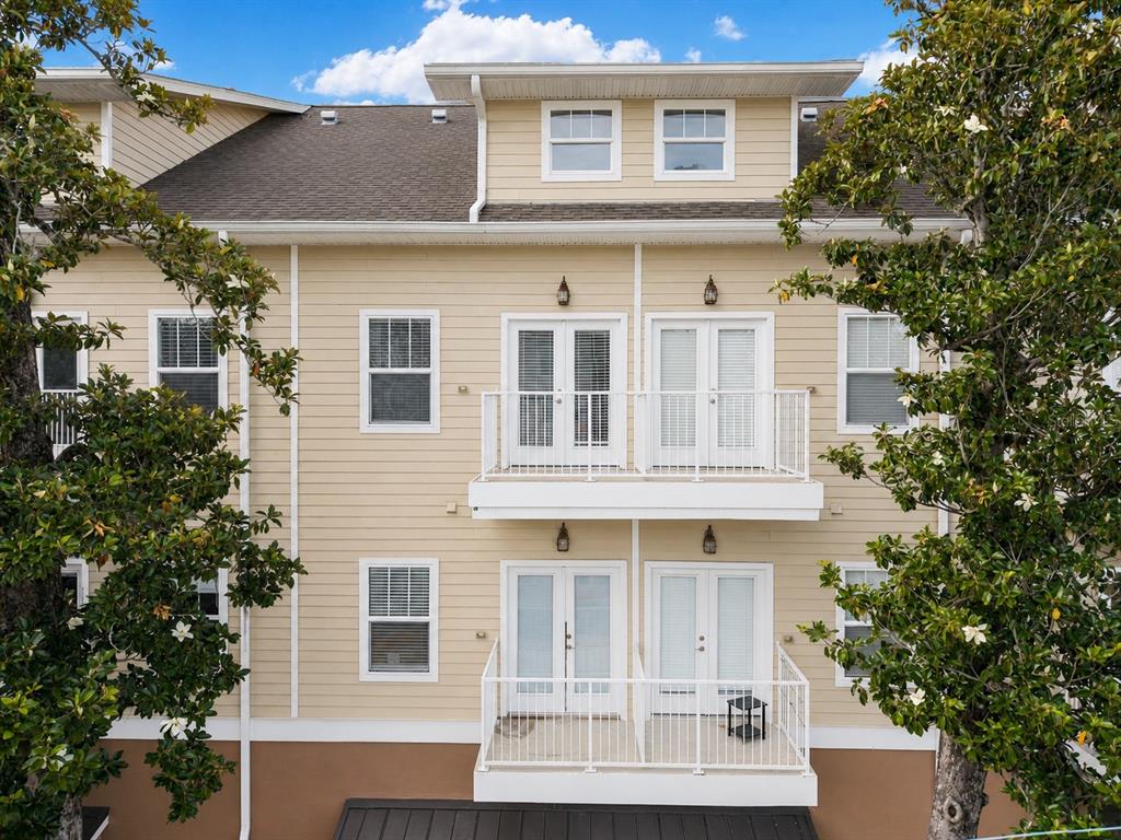 The exterior of a three-story tan building features two levels of stacked balconies with doors — 1500 NW 4TH AVENUE UNIT 311, GAINESVILLE, FL