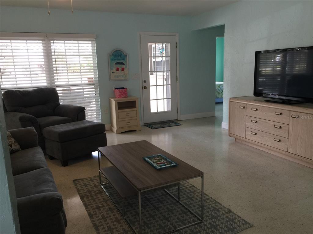A living room features light blue walls, a gray sofa, a coffee table, and a television — 7429 BROUGHTON STREET, SARASOTA, FL