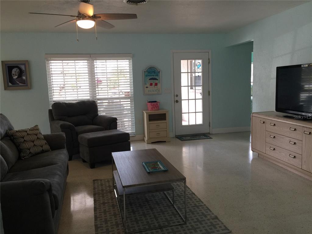 A living room features light blue walls, tile flooring, a ceiling fan, and a television console — 7429 BROUGHTON STREET, SARASOTA, FL