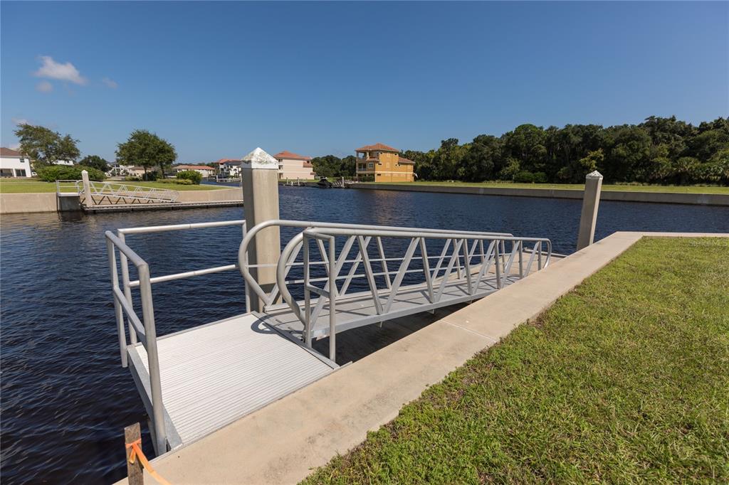 A metal gangway leads from a concrete bulkhead to a floating dock on a canal — 12 CUTTER COURT, PALM COAST, FL