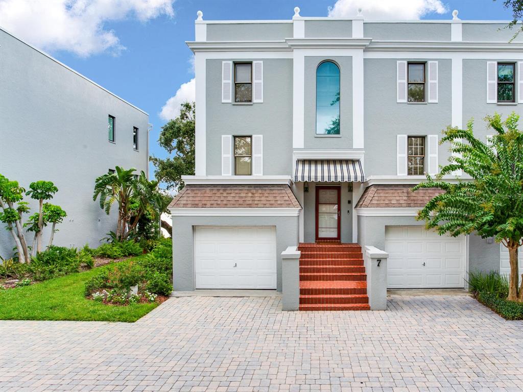 A three-story gray townhouse features two garage doors, a red brick staircase, and white trim — 5010 BAYSHORE BOULEVARD UNIT 7, TAMPA, FL
