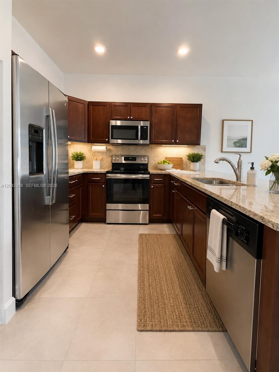 A kitchen features dark wood cabinets, stainless steel appliances, and granite countertops — 5336 Ashley River Rd, West Palm Beach FL 33417, WEST PALM BEACH, FL