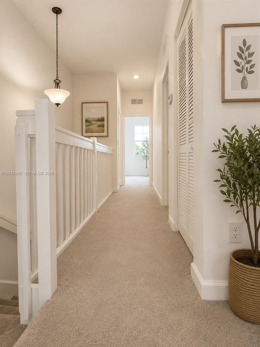 A carpeted hallway features a white wooden railing, a hanging pendant light, and louvered doors — 5336 Ashley River Rd, West Palm Beach FL 33417, WEST PALM BEACH, FL