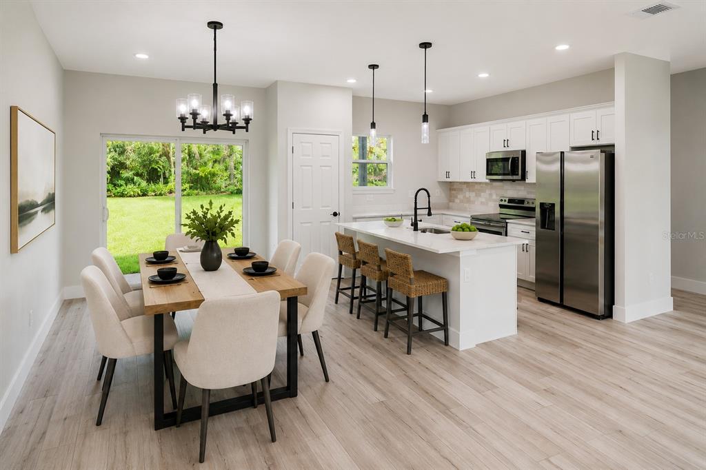 A kitchen and dining area with white cabinets, a central island, and light wood flooring — 8596 N VINCE DRIVE, CITRUS SPRINGS, FL
