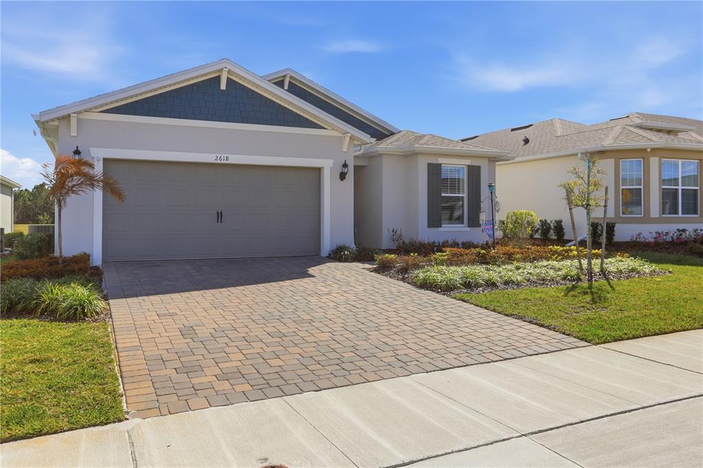 A single-story house with a paved driveway, two-car garage, and blue shingle accents — 2618 DEL WEBB DRIVE, MINNEOLA, FL