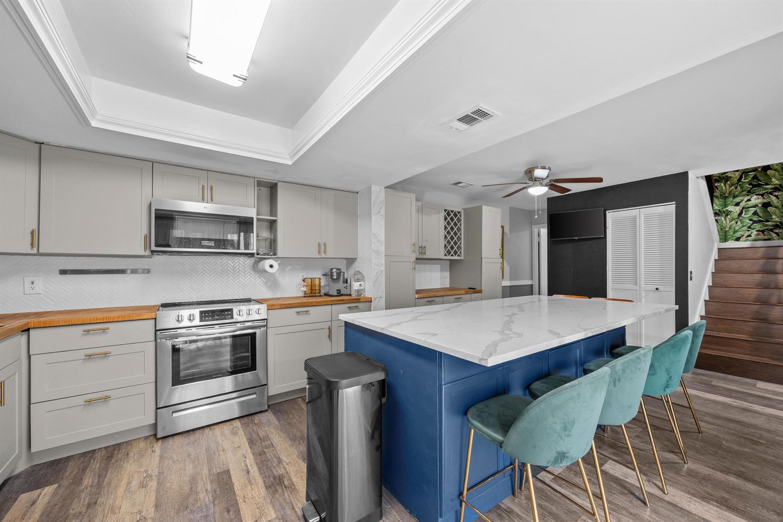 A kitchen features gray cabinets, wood countertops, a blue island with seating, and wood flooring — 1520 Shaker Circle, Wellington FL 33414, WELLINGTON, FL