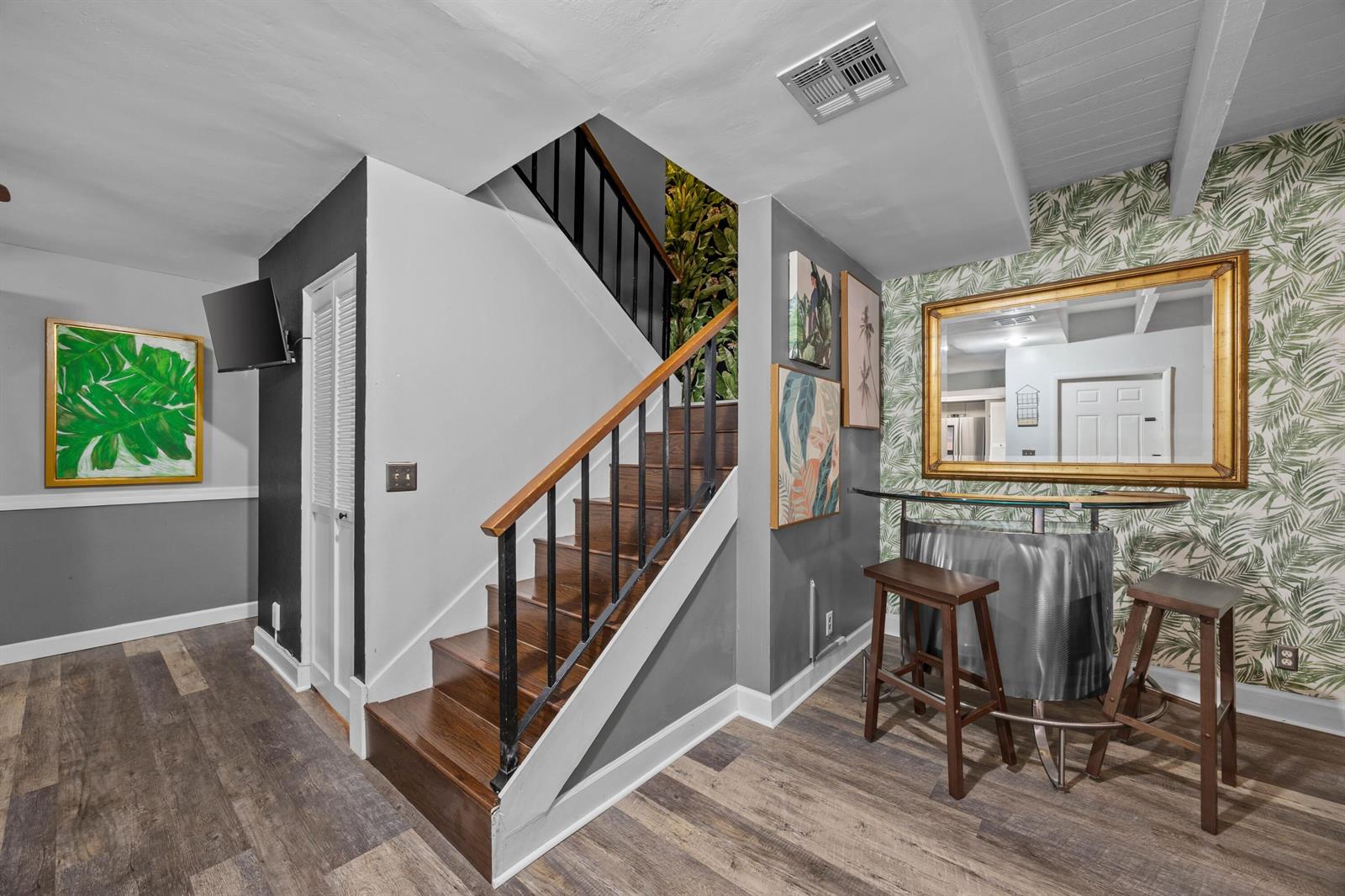 A staircase with wooden treads and black railings sits next to a small bar area — 1520 Shaker Circle, Wellington FL 33414, WELLINGTON, FL