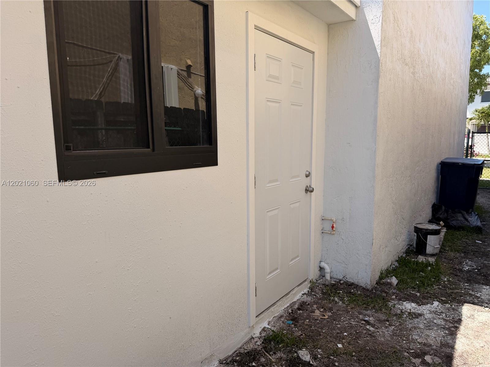 An exterior view shows a white door and a window on a stucco wall — 16536 SW 54th St # 1, Miami FL 33185, MIAMI, FL